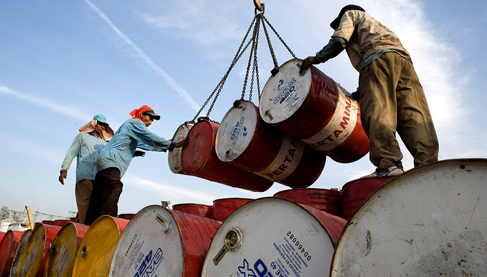 Dos operarios indonesios descargan barriles cargados de petróleo de la compañía Pertamina en el puerto de Yakarta, Indonesia, el 21 de septiembre. EFE/Adi Weda.