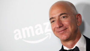 Jeff Bezos, CEO de Amazon, a la derecha, con el logotipo de su empresa, de fondo, a la izquierda.