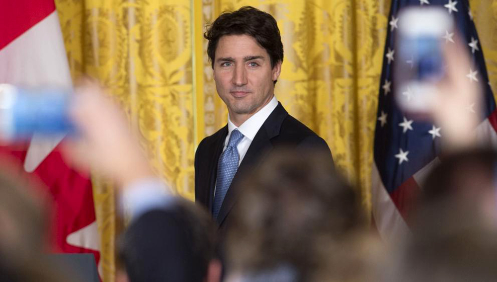 Justin Trudeau, primer ministro de Canadá, frente a periodistas, con una cortina amarilla de fondo.