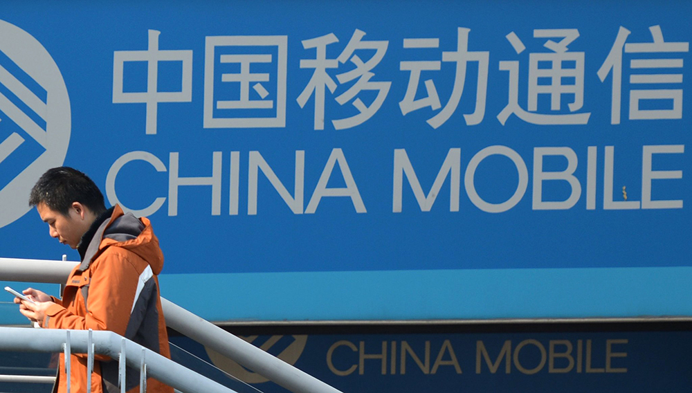 A man uses his mobile phone as he walks past a China Mobile sign on a street in Shanghai on December 23, 2013. AFP PHOTO/Peter PARKSPETER PARKS/AFP/Getty Images