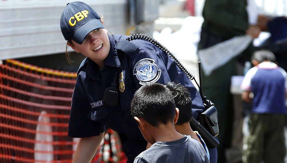 A U.S. Customs and Border Protection officer helps two young boys pick out clothes June 18, 2014, as they join hundreds of mostly Central American immigrant children being processed and held at the U.S. Customs and Border Protection placement center in Nogales, Ariz. (Photo: Ross D. Franklin, AP)