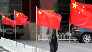 A man walks past Chinese national flags tied to iron fences at Chaoyang Hospital, where blind activist Chen Guangcheng was reported to be staying at, in Beijing May 2, 2012. REUTERS/Jason Lee
