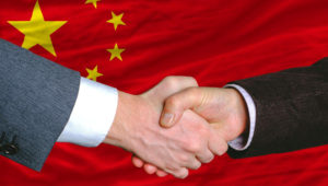 Businessmen handshake after good deal in front of China flag — Stock Photo