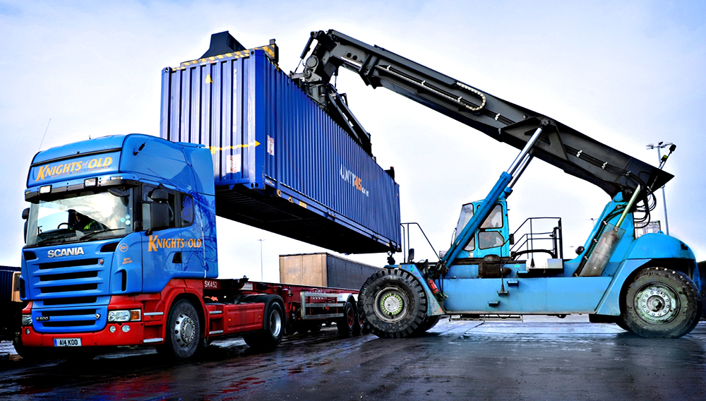 Una grúa levanta un contenedor de carga marítima y lo coloca sobre un camión Scania, en un terminal de contenedores.