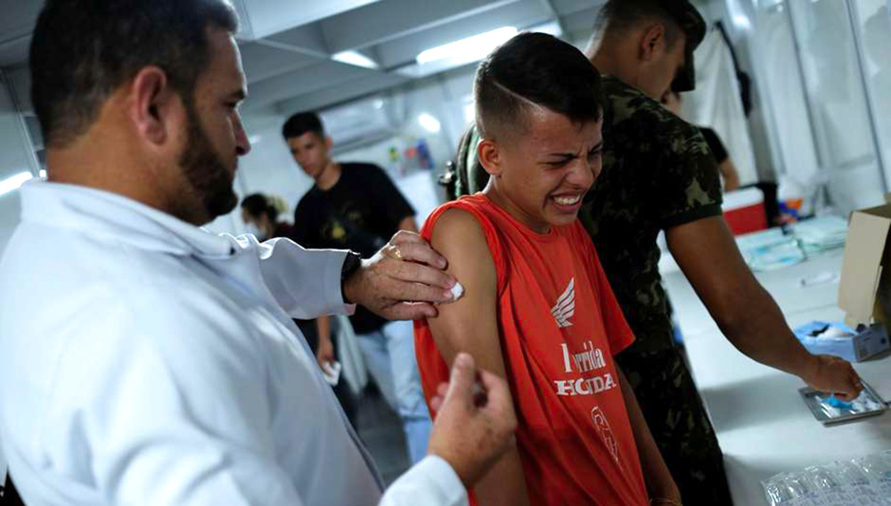 Un niño venezolano recibe vacunación gratuita de parte de un voluntario tras exhibir su pasaporte en el control fronterizo de Pacaraima, en el estado brasileño de Roraima, 9 de agosto de 2018. REUTERS/Nacho Doce