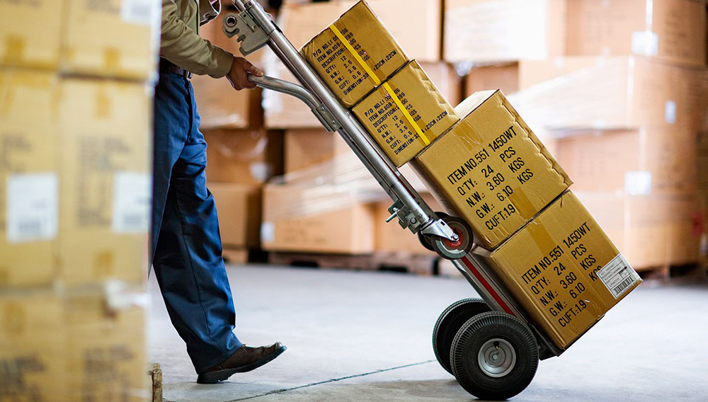 Empleado de logística una empresa llevando cajas con mercadería.