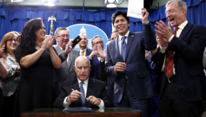 State Sen. Kevin de León (D-Los Angeles) holds up his environmental measure Senate Bill 100 after it was signed into law by Gov. Jerry Brown on Monday in Sacramento. (Rich Pedroncelli / Associated Press)