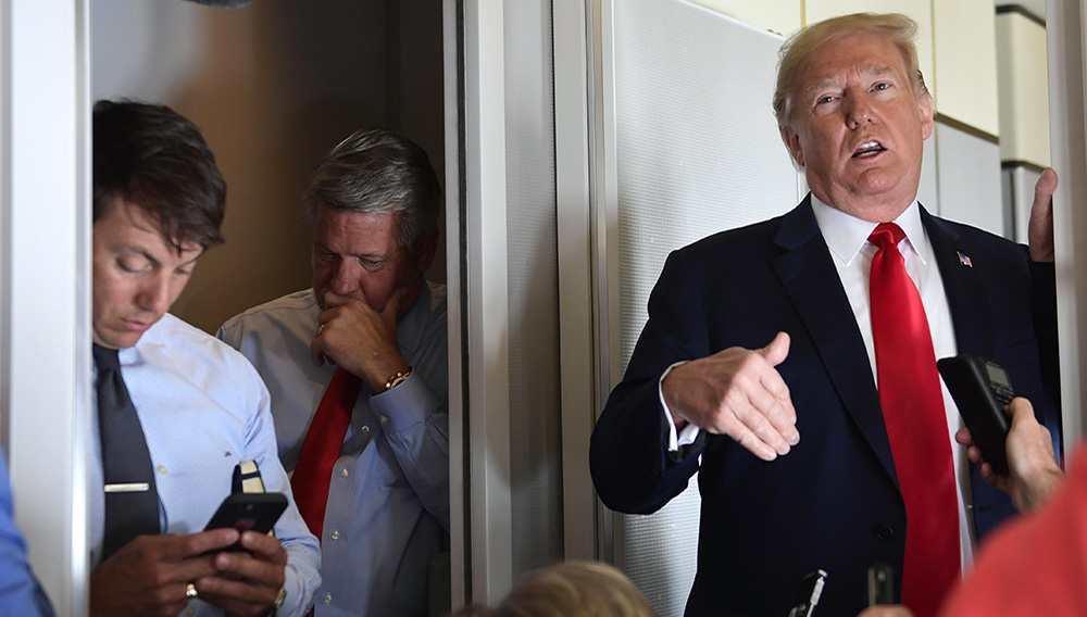 El subsecretario de prensa de la Casa Blanca Hogan Gidley (izquierda) y el subjefe del equipo de comunicación de la Casa Blanca Bill Shine (al centro) escuchan mientras el presidente Donald Trump habla con reporteros en un vuelo desde Billings, Montana, a Fargo, Dakota del Norte, el viernes 7 de septiembre de 2018. (AP Foto/Susan Walsh)