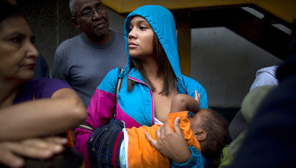 Madeley Vásquez, de 16 años, da el pecho a su hijo de uno Joangel mientras espera en el exterior de un supermercado para comprar comida en Caracas, Venezuela. Foto de AP.