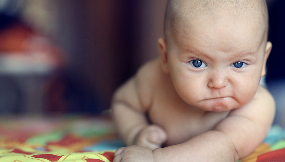 Bebé de ojos azules mirando a la cámara con una expresión seria. Shutterstock.