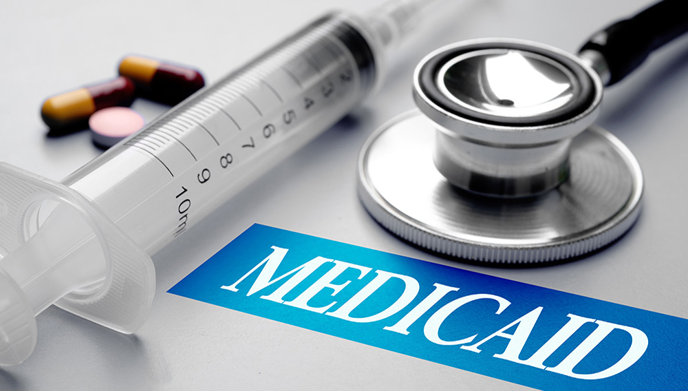 Medicaid, health concept. Stethoscope, syringe and pills on grey background. Shutterstock