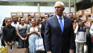 El vicepresidente estadounidense Mike Pence está de pie en un cuarto lleno de ayuda humanitaria destinada a Venezuela antes de una reunión con un grupo de migrantes venezolanos en Bogotá, Colombia, el lunes 25 de febrero de 2019. (AP Foto/Martin Mejia)