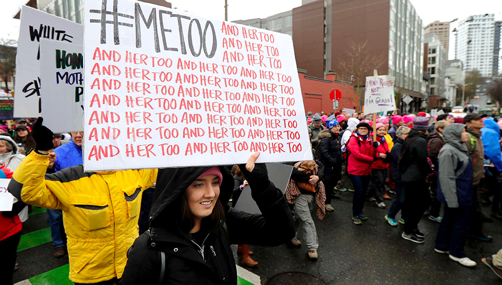 Una mujer lleva un cartel que dice "#MeToo", en alusión al movimiento #yotambién que está replanteando las relaciones entre hombre y mujeres, acompañado por decenas de "y ella también", durante una protesta en Seattle el 20 de enero del 2018. (AP Photo/Ted S. Warren)