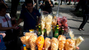 FILE - In this July 5, 2016 file photo, a street vendor sells fried snacks packaged in plastic bags in Mexico City. Mexico City lawmakers announced on Thursday, May 9, 2019 they have passed a ban on plastic bags, utensils and other disposable plastic items to take effect at the end of 2020, giving businesses more than a year to make the switch to biodegradable products. (AP Photo/Eduardo Verdugo, File)