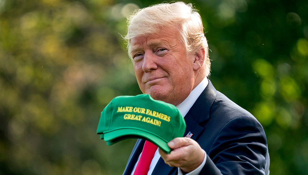 President Donald Trump hold up hats that read "Make Our Farmers Great Again!" as he walks across the South Lawn before boarding Marine One at the White House in Washington, Thursday, Aug. 30, 2018, for a short trip to Andrews Air Force Base, Md., and then on to Evansville, Ind., for a rally. (AP Photo/Andrew Harnik)