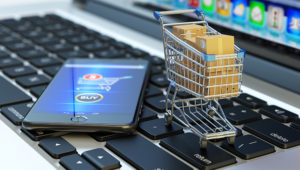 Online shopping, internet purchases and e-commerce concept, modern mobile phone with buy button on the screen and shopping cart full of package boxes on computer laptop keyboard. Shutterstock