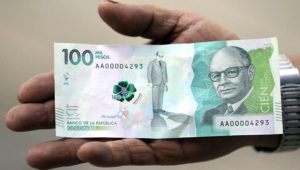 Un hombre muestra el nuevo billete colombiano de 100.000 pesos en Bogotá, Colombia, jueves 31 de marzo de 2016. El billete, el de mayor denominación en el país, entró en circulación el 31 de marzo Equivale a unos 33 dólares. (AP Foto/Fernando Vergara)