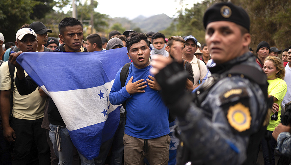 Honduran migrants walking in a group stop before Guatemalan police near Agua Caliente, Guatemala, Thursday, Jan. 16, 2020, on the border with Honduras. Less-organized migrants, tighter immigration control by Guatemalan authorities and the presence of U.S. advisers have reduced the likelihood that the hundreds of migrants who departed Honduras will form anything like the cohesive procession the term “caravan” now conjures. (AP Photo/Santiago Billy)