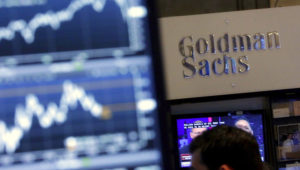 In this Oct. 16, 2014, file photo, a screen at a trading post on the floor of the New York Stock Exchange is juxtaposed with the Goldman Sachs booth. (AP Photo/Richard Drew, File)