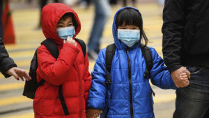 Children wearing face masks cross a road during a Lunar New Year of the Rat public holiday in Hong Kong on January 27, 2020, as a preventative measure following a coronavirus outbreak which began in the Chinese city of Wuhan. (Photo by Anthony WALLACE / AFP) (Photo by ANTHONY WALLACE/AFP via Getty Images)