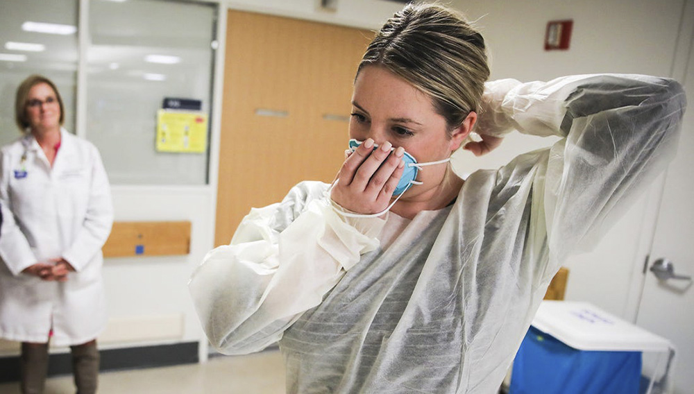 Kaylen Smith demonstrates how to don the protective gear that must be worn when dealing with patients with an infectious disease as Massachusetts General Hospital in Boston prepares for a possible surge in coronavirus patients on Feb. 27, 2020. Erin Clark/The Boston Globe via Getty Images