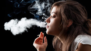 Woman smoking a cigarette on black background. Photo: Adobe Stock