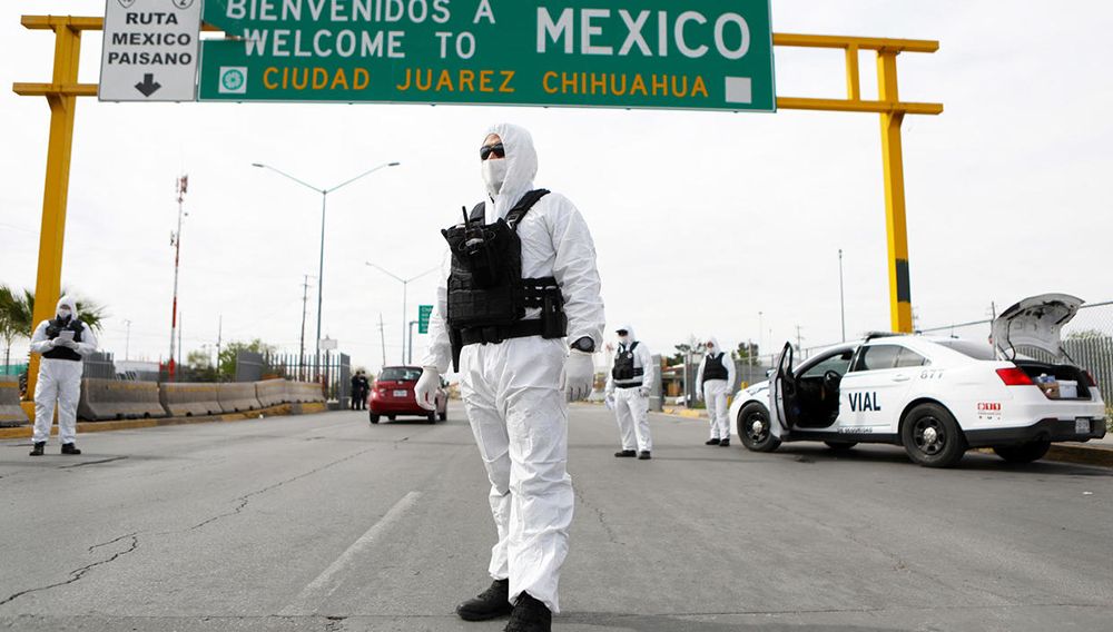 Miembros de la Policía del Estado de Chihuahua, vestidos con trajes protectores, participan en una campaña de información y prevención contra la pandemia de coronavirus -COVID-19-, en el Puente Internacional Córdoba-De las Américas en Ciudad Juárez, Chihuahua, México, el 29 de marzo de 2020. HERIKA MARTINEZ AFP