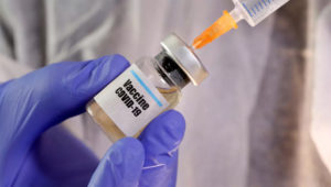A woman holds a small bottle labbeled with a "Vaccine COVID-19" sticker and a medical syringe in this illustration taken April 10, 2020. © REUTERS/Dado Ruvic/Illustration