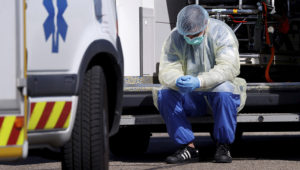 A health worker wearing a protective gear takes a break during transfer operations of patients infected with coronavirus disease (COVID-19) from Strasbourg to Germany and Switzerland, France March 30, 2020. REUTERS/Christian Hartmann