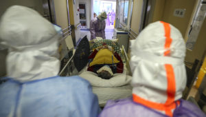 This photo taken on February 28, 2020 shows medical staff transferring a patient infected by the COVID-19 coronavirus at the Red Cross hospital in Wuhan in China's central Hubei province. - China on March 1 reported 35 more deaths from the new coronavirus, taking the toll in the country to 2,870. (Photo by STR / AFP) / China OUT