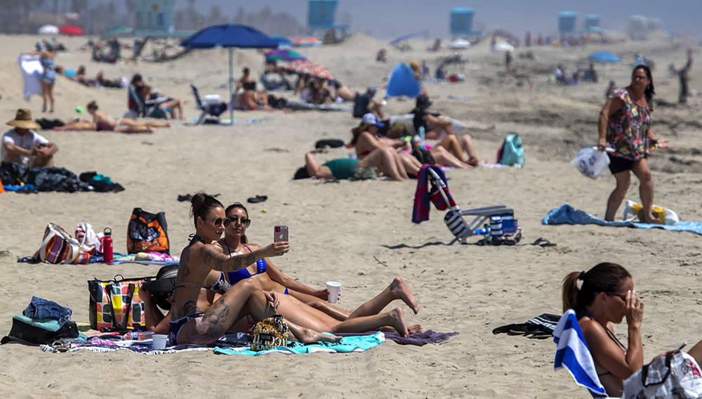 Cailin Healy, and an unidentified friend, both of Calabasas, take a selfie together as beach-goers enjoy warm summer-like weather amid state and city social distancing regulations mandated by Gov. Newsom in Huntinton Beach, CA, on April 22, 2020. Allen J. Schaben | Los Angeles Times via Getty Images