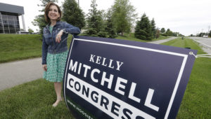 Indiana State Treasurer Kelly Mitchell stands by a campaign sign, Thursday, May 28, 2020, in Westfield, Ind. Mitchell is a candidate for Indiana's 5th Congressional District. (AP Photo/Darron Cummings)