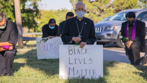 In this June 1, 2020, photo provided by the Catholic Diocese of El Paso, Bishop Mark Seitz, center, kneels with other demonstrators at Memorial Park holding a Black Lives Matter sign in El Paso, Texas. Pope Francis called Seitz unexpectedly after he was photographed at the protest. (Fernie Ceniceros/Catholic Diocese of El Paso via AP)