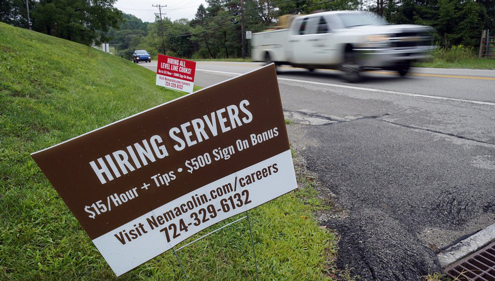 FILE - In this Wednesday, Sept. 2, 2020, file photo help wanted signs for servers and cooks at Nemacolin Woodlands Resort and Spa are displayed along route 40 at the entrance to the resort in Farmington, Pa. U.S. employers advertised more jobs but hired fewer workers in July, sending mixed signals about a job market in the wake of the coronavirus outbreak. (AP Photo/Gene J. Puskar, File)