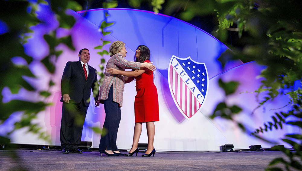 In this July 14, 2016 photo Democratic presidential candidate Hillary Clinton, accompanied by then-LULAC President Roger C. Rocha, Jr., left, hugs University of Texas student Dreamer Lizeth Urdiales, right, as she arrives to speaks at the 87th League of United Latin American Citizens National Convention at the Washington Hilton in Washington. (AP Photo/Andrew Harnik, File)