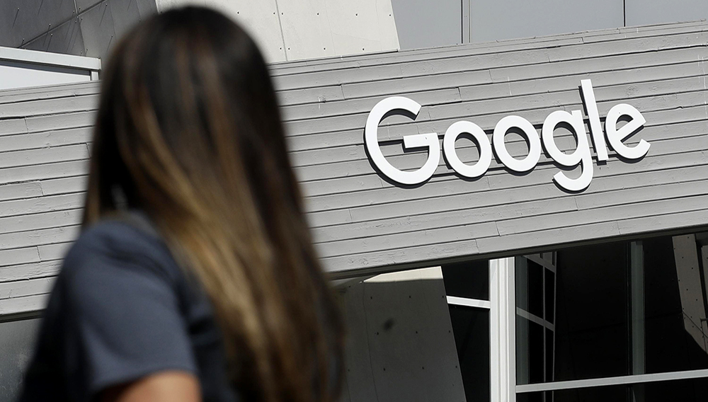 FILE - In this Sept. 24, 2019, file photo, a woman walks below a Google sign on the campus in Mountain View, Calif. (AP Photo/Jeff Chiu, File)