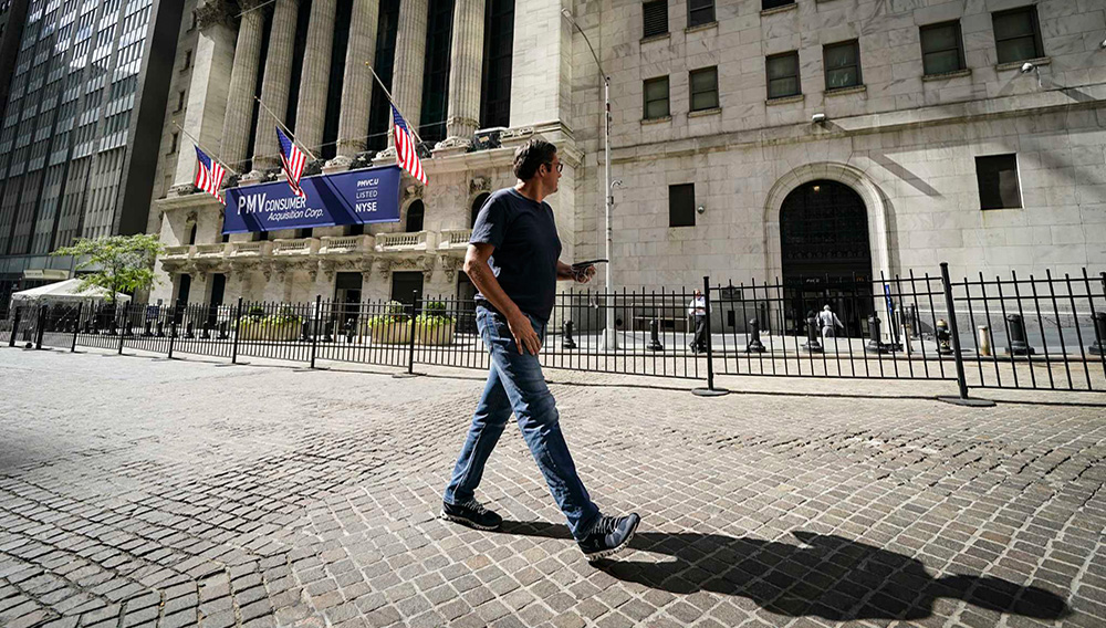 A pedestrian pass the New York Stock Exchange, Friday, Oct. 2, 2020, in New York. Stocks around the world are falling sharply Wednesday, Oct. 28, on worries the worsening pandemic will push governments to bring back restrictions on businesses. (AP Photo/John Minchillo)