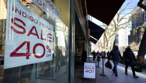 Shoppers pass an Indigo Friday 40% Off sign Saturday, Nov. 28, 2020, on Chicago's famed Magnificent Mile shopping district. (AP Photo/Charles Rex Arbogast)
