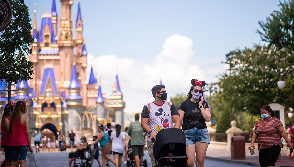 Guests wearing required face masks due to the COVID-19 pandemic stroll along Main Street, U.S.A. in front of Cinderella Castle at Walt Disney World Resort’s Magic Kingdom on Wednesday, August 12, 2020, in Lake Buena Vista, Fla. (Photo by Charles Sykes, Invision/AP)
