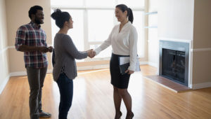 Young couple buying new house, handshaking with realtor in agreement. | Photo: iStock