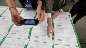 In this Nov. 6, 2020, photo, a canvas observer photographs Lehigh County provisional ballots as vote counting in the general election continues in Allentown, Pa. (AP Photo/Mary Altaffer, File)