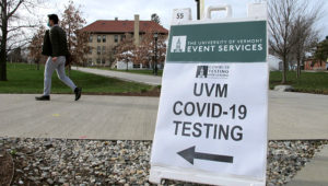 In this Nov. 12, 2020, photo, a University of Vermont student walks toward a tent leading to a COVID-testing site on campus in Burlington, Vt. As coronavirus cases are surging around the U.S., some colleges and universities are rethinking some of their plans for next semester. (AP Photo/Lisa Rathke)
