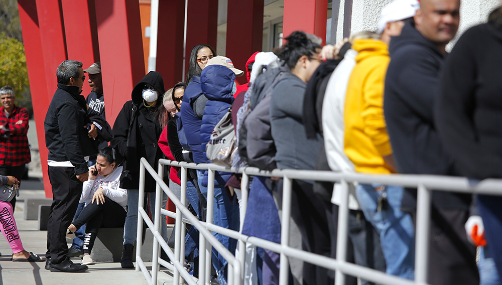 In this March 17, 2020, file photo, people wait in line for help with unemployment benefits at the One-Stop Career Center in Las Vegas. Americans who struggled through 2020 could face more hardship in the year ahead as pandemic related payments and protections come to an end. (AP Photo/John Locher, File)