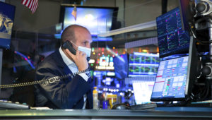 In this photo provided by the New York Stock Exchange, specialist James Denaro works at his post on the trading floor, Thursday Dec. 3, 2020. U.S. stocks are inching further into record heights Thursday, as Wall Street continues to coast following its rocket ride last month powered by hopes for coming COVID-19 vaccines. (Nicole Pereira/New York Stock Exchange via AP)