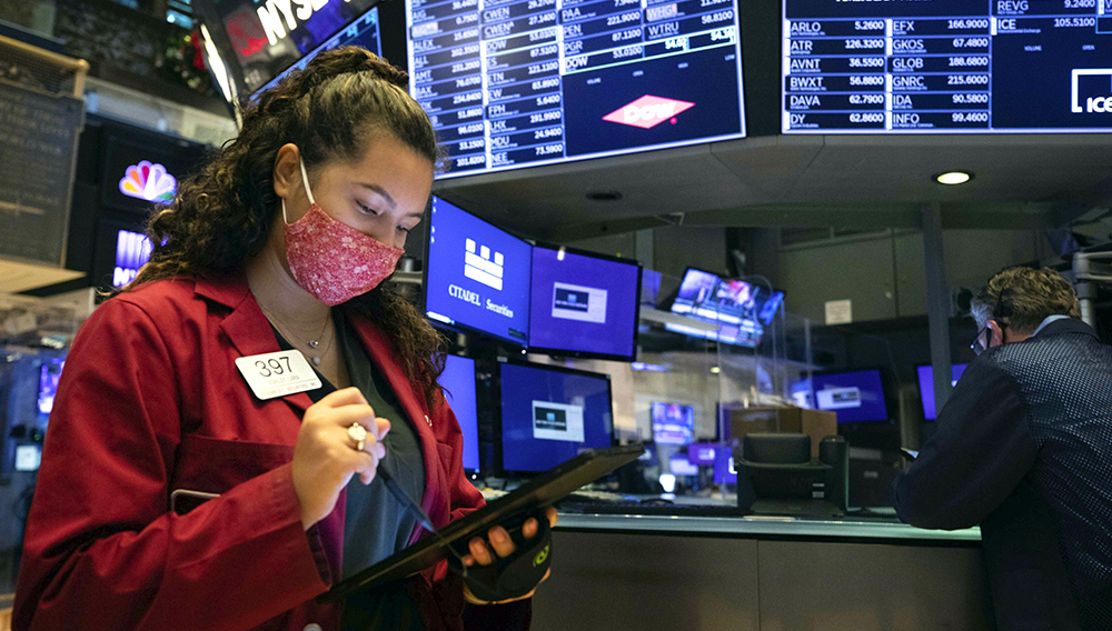 In this photo provided by the New York Stock Exchange, trader Ashley Lara uses her handheld device as she works on the trading floor, Tuesday, Dec. 1, 2020. (Colin Ziemer/New York Stock Exchange via AP)