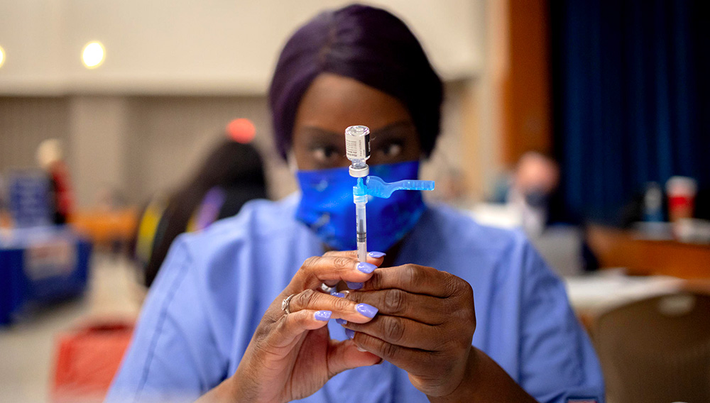 A health care worker prepares a dose of the Pfizer-BioNTech COVID-19 vaccine last week at West Philadelphia High School in Philadelphia. HANNAH BEIER / BLOOMBERG VIA GETTY IMAGES