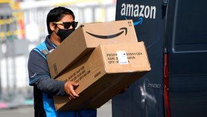 An Amazon.com Inc. delivery driver carries boxes into a van outside of a distribution facility on February 2, 2021 in Hawthorne, California. (Photo by PATRICK T. FALLON/AFP via Getty Images)