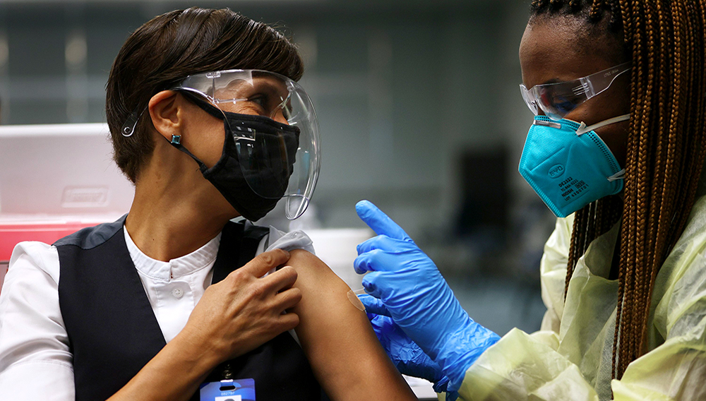 Angelica Segura Miravete, who works for AeroMexico, gets a Pfizer-BioNtech COVID-19 vaccination from a healthcare worker at Miami International Airport on May 10, 2021 in Miami, Florida. | PHOTO: Joe Raedle/Getty Images/AFP