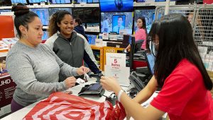 Target employee Jessa Ato (right) rings up a purchase in the electronics department for Silvana Molina (left) and her daughter, Shanayah, on Friday morning. | PHOTO: DEVON RAVINE/DAILY NEWS