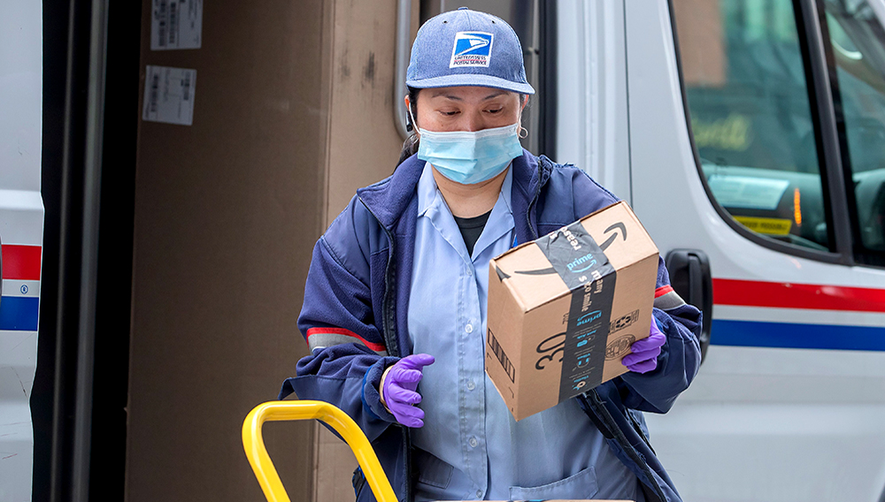 A United States Postal Service (USPS) carrier wears a mask and gloves as personal protective equipment while making deliveries in Washington, DC, USA, 01 April 2020. | PHOTO: ERIK S LESSER/EPA-EFE/Shutterstock